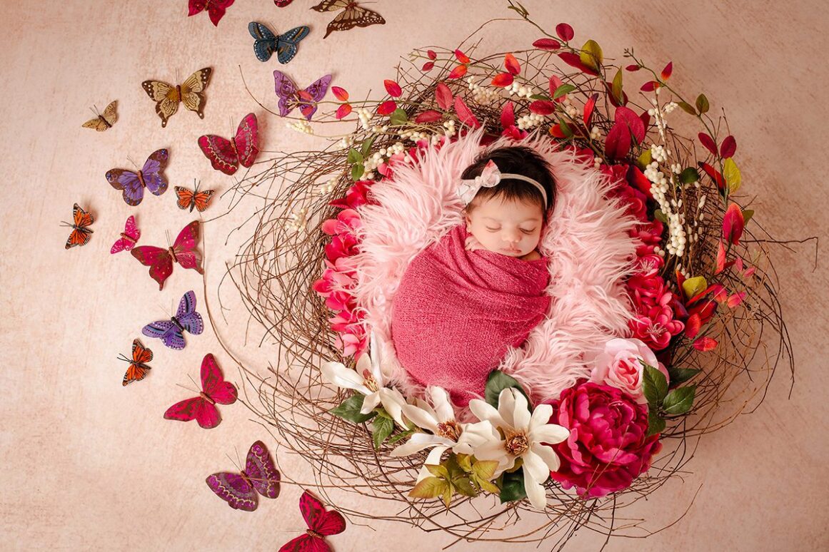 newborn in wreath with flowers and butterflies.